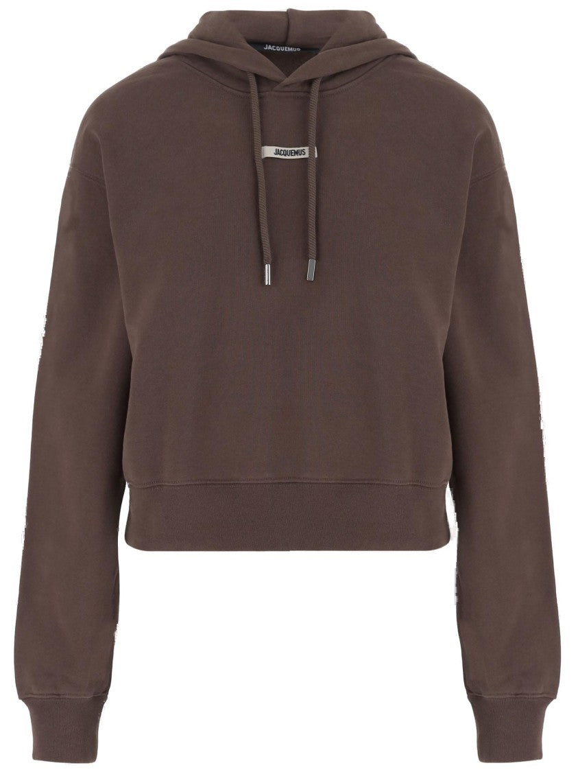 Короткий коричневый худи с отделкой из галуна и логотипом Jacquemus
Короткий коричневый худи с отделкой из галуна и логотипом Jacquemus