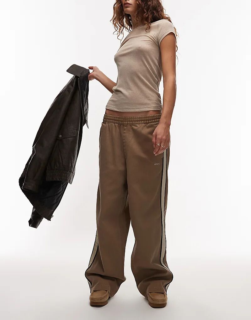 Obey Astrid, надевает мешковатые брюки с полосками по бокам в коричневом и бежевом цветах.
Obey Astrid, надевает мешковатые брюки с полосками по бокам в коричневом и бежевом цветах.