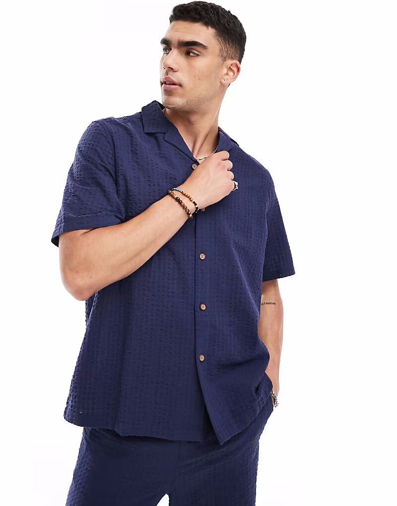 ASOS DESIGN coord 90-х годов свободная рубашка с короткими рукавами из фактурной ткани сирсакер темно-синего цвета 
ASOS DESIGN coord 90-х годов свободная рубашка с короткими рукавами из фактурной ткани сирсакер темно-синего цвета