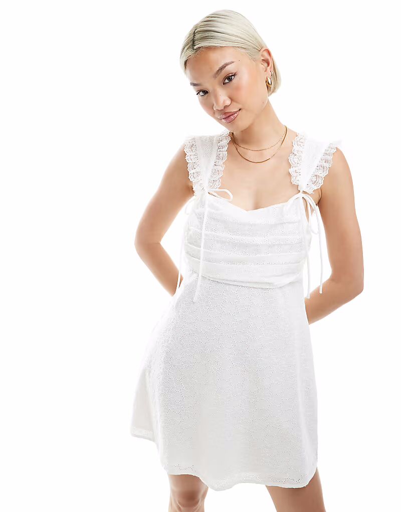 Эксклюзивное мини-платье Frolic белого цвета с кружевной отделкой, присборенным бюстом и бантом The Frolic
Эксклюзивное мини-платье Frolic белого цвета с кружевной отделкой, присборенным бюстом и бантом The Frolic
