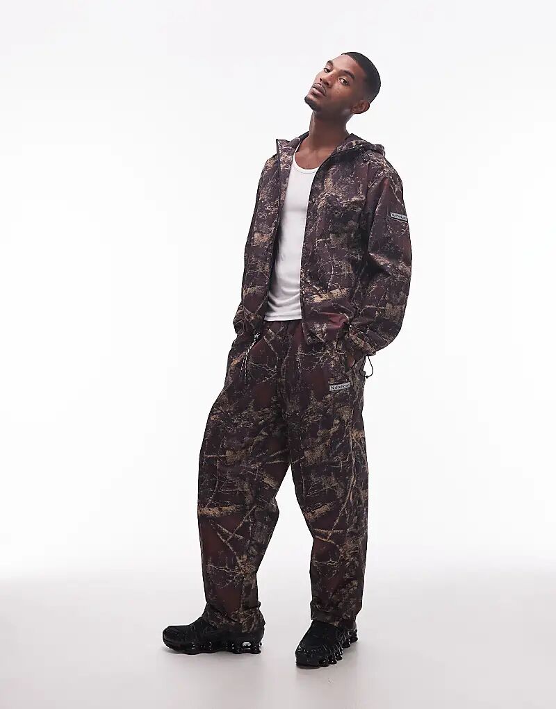 Нейлоновые брюки No Problemo Glitch с темным камуфляжным принтом в виде настоящего дерева 
Нейлоновые брюки No Problemo Glitch с темным камуфляжным принтом в виде настоящего дерева