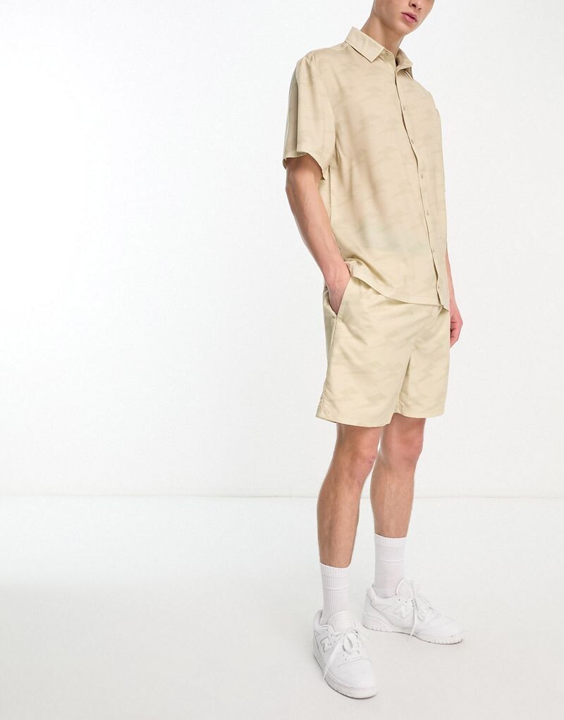 

Ellesse – Капри – Бежевая рубашка с узором молний, ​​часть комплекта
