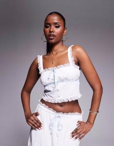 Эксклюзивный укороченный топ белого цвета с отделкой из текстурированного кружева и контрастным синим бантом Kaiia