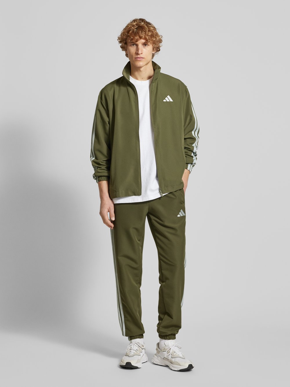 

Спортивный костюм с характерными полосками на этикетке ADIDAS SPORTSWEAR, оливковый