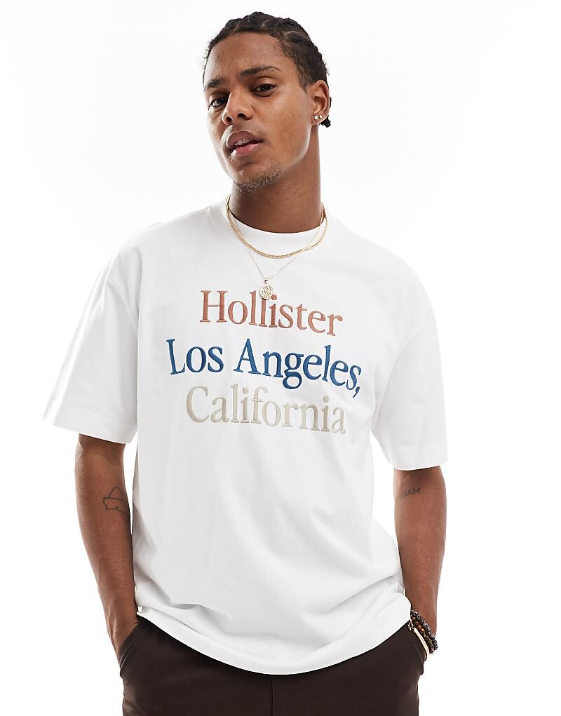

Hollister – белая толстая футболка свободного кроя с ярким логотипом
