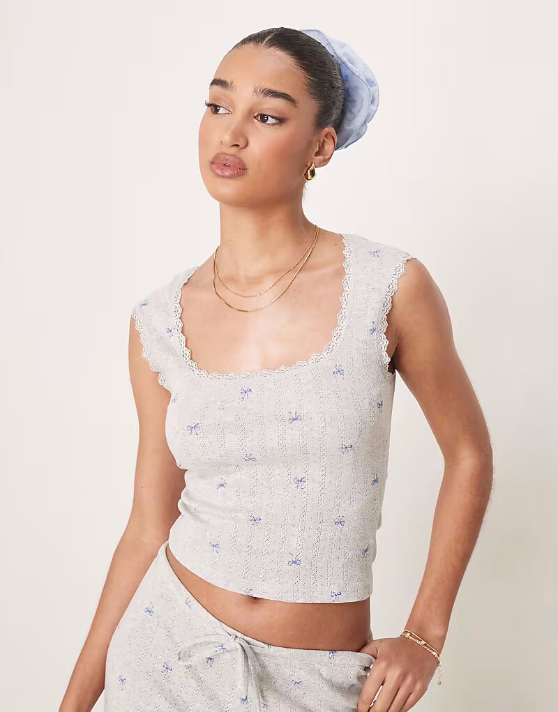 

Жилет Gina Tricot из хлопка с ажурной вышивкой по краю и синими бантами в сером меланжевом цвете.